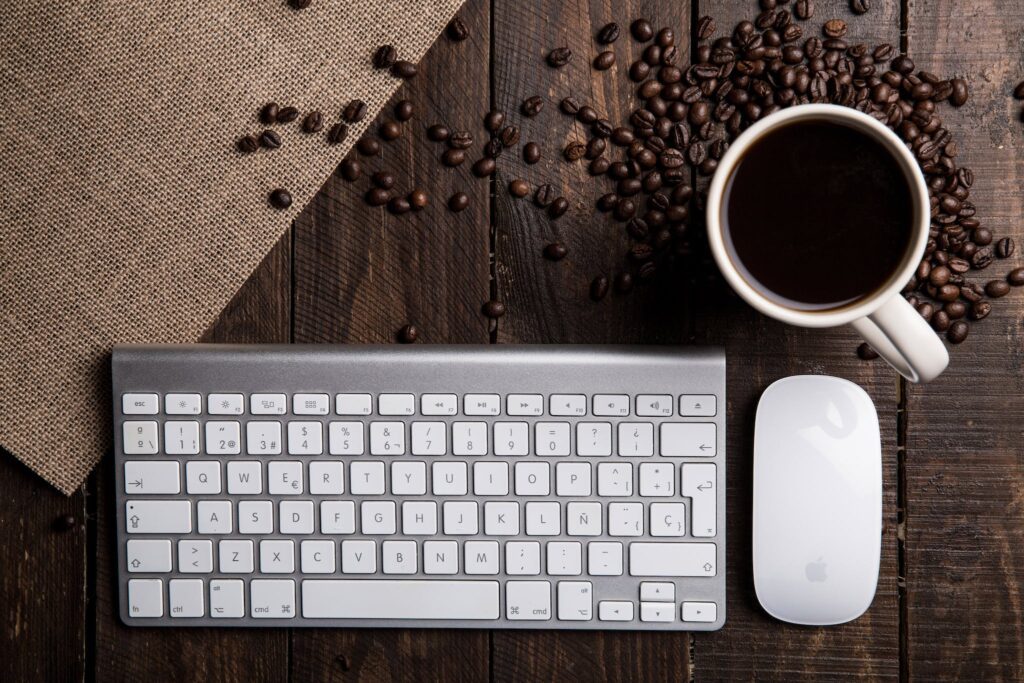 Flat Lay Photography of Apple Magic Keyboard, Mouse, and Mug Filled With Coffee Beside Beans