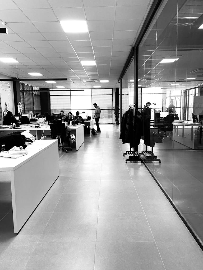 Black and white of anonymous employees working together in modern office with glass walls | Startup Operations